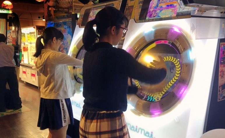 dos adolescentes juegan en una consola electrónica con luces y colores